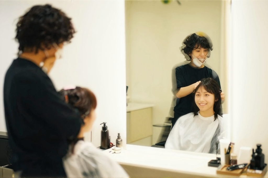 美容院で施術後にお客様と会話するスタイリスト